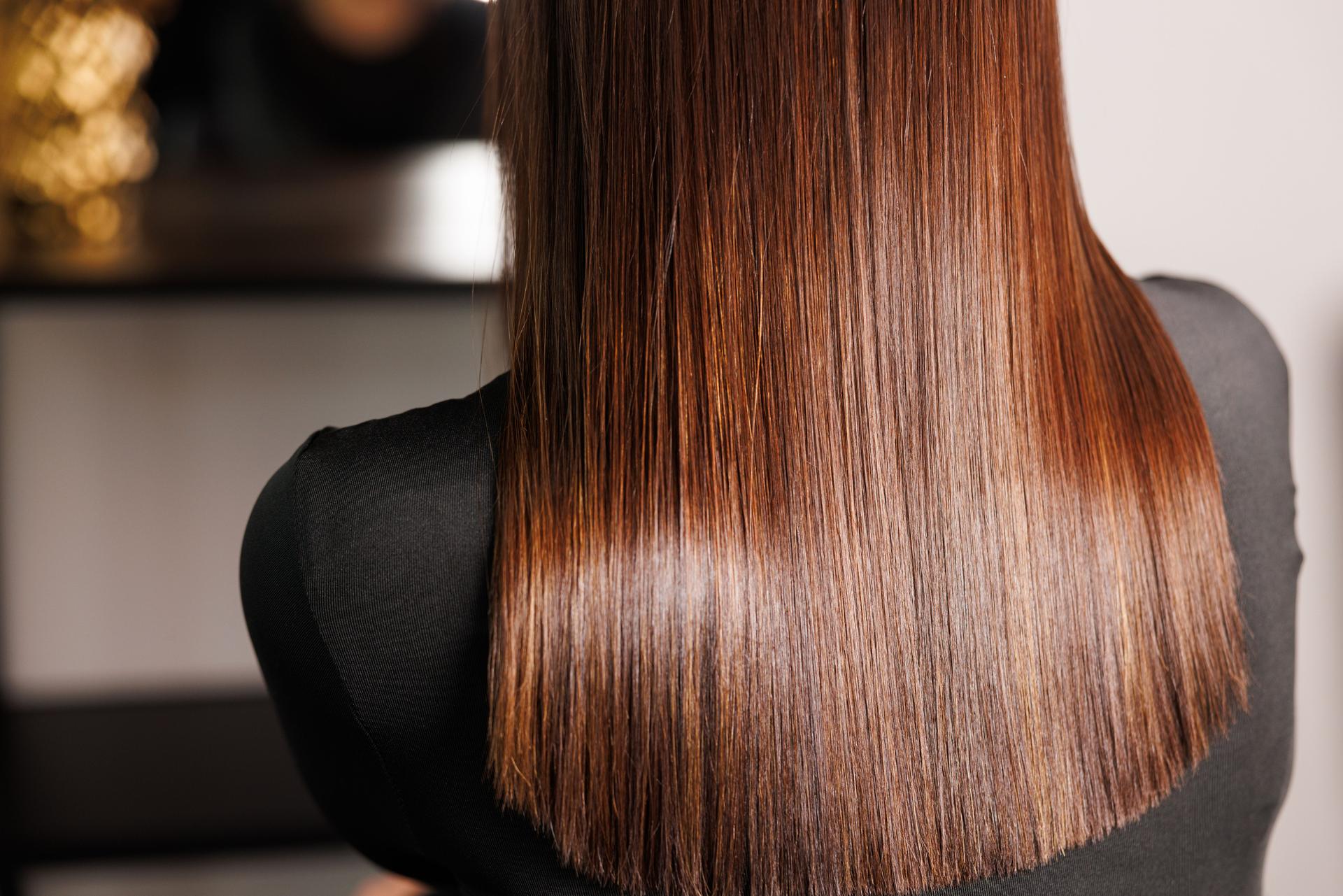 Woman with layered hair and bangs is in beauty salon chair in front of mirror