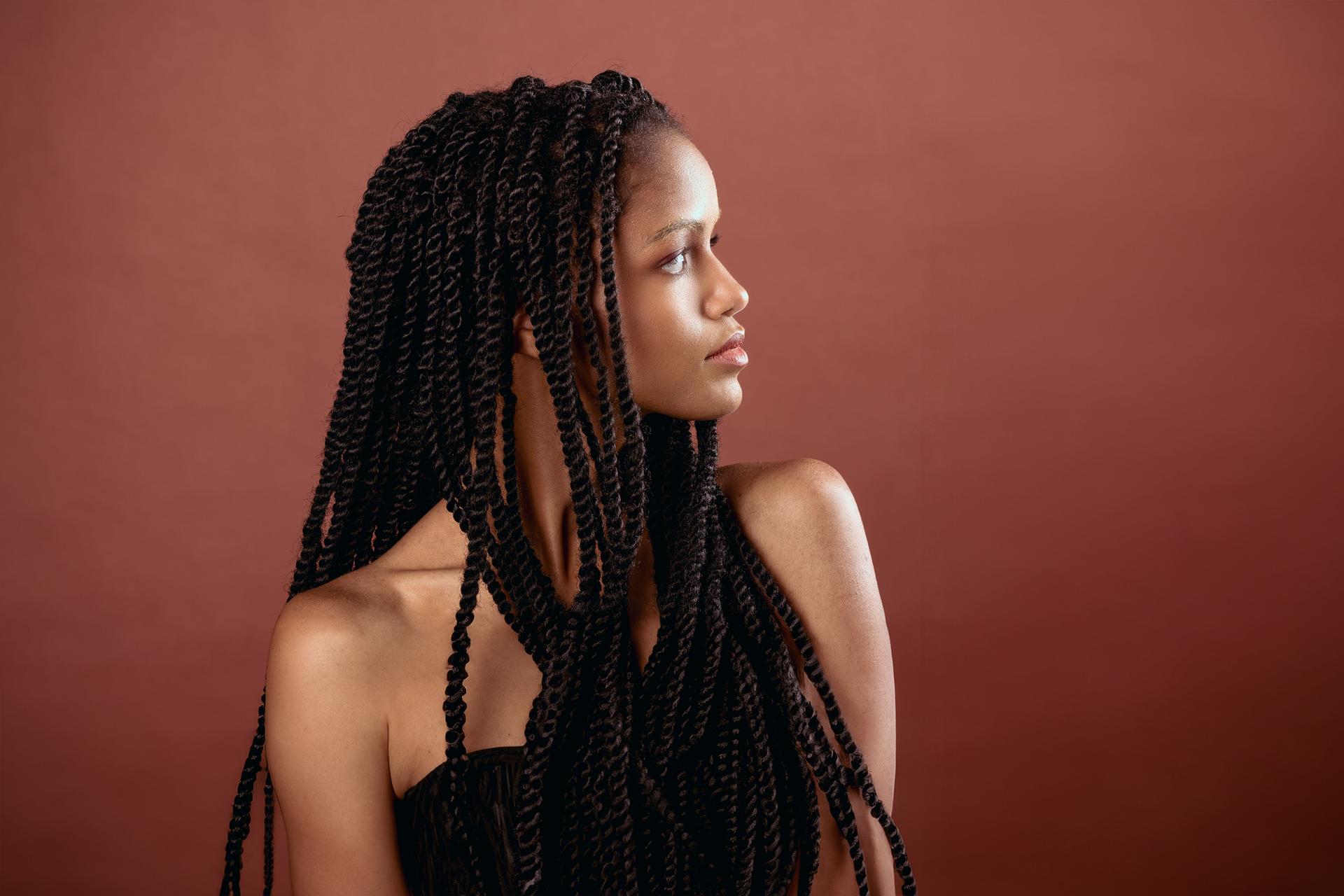 Sitting black woman with Afro braids in light