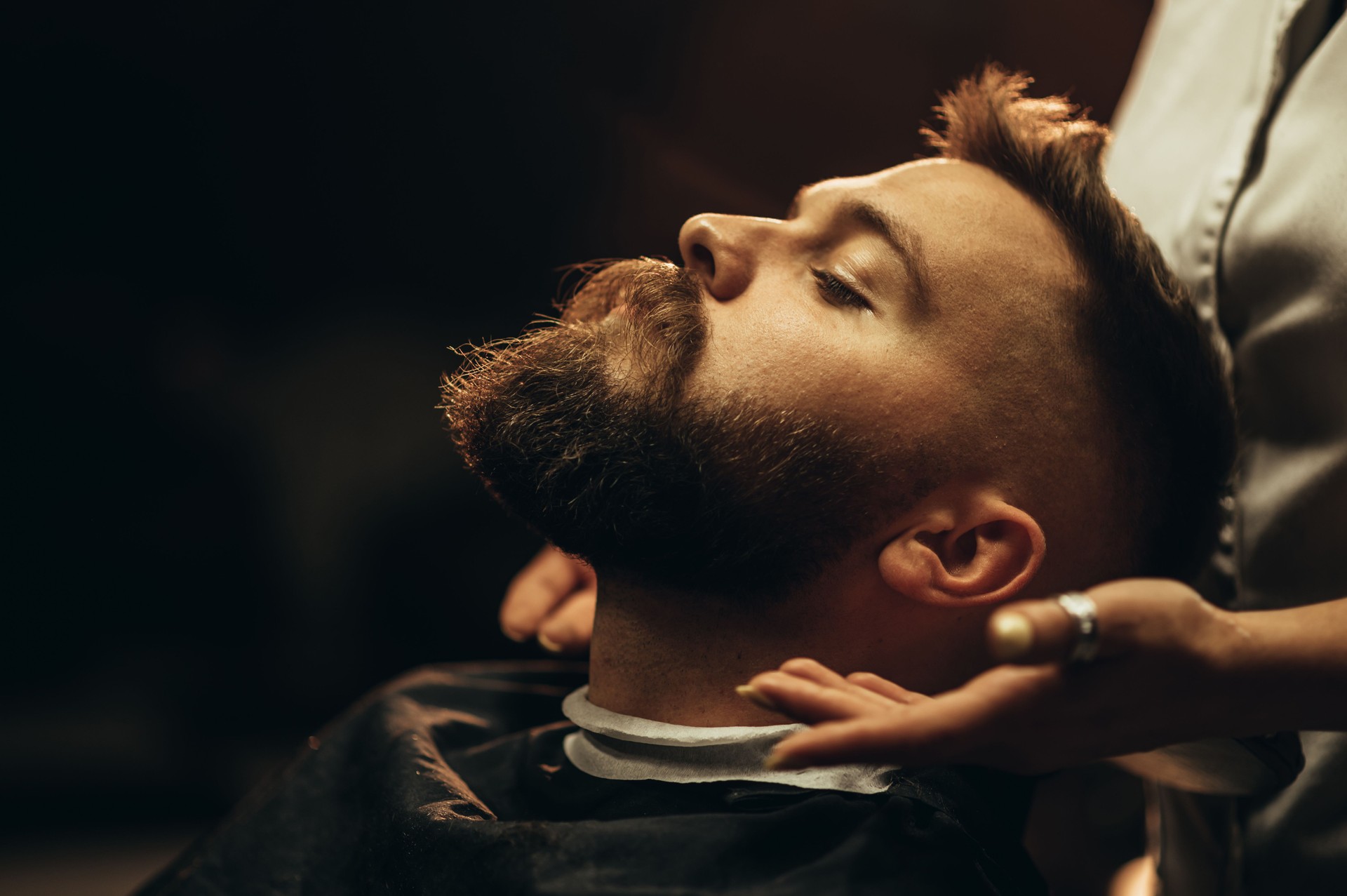 Close shot of a young man beard while he is sitting at a barbershop